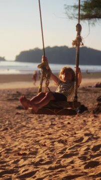 Young boy swinging on a rustic wooden rope swing at the beach a child enjoying