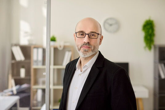 Businessman portrait in office shows leadership. Confident manager and professional executive with glasses in workspace, showing success, trust and confidence. Strong leadership and trust theme.