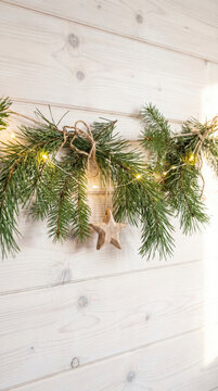 Pine garland with wooden star and fairy lights on whitewashed timber wall for Christmas