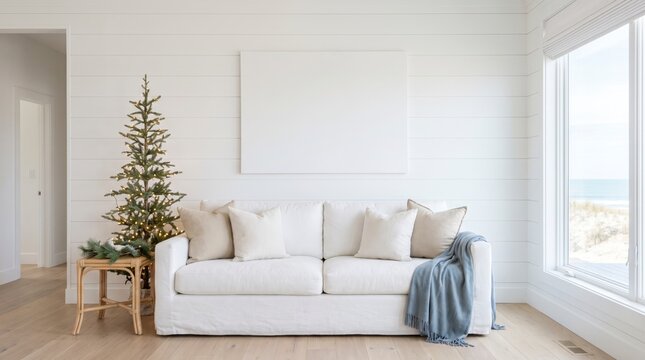 Coastal living room with white sofa, blank canvas, mini Christmas tree and blue throw by sea view