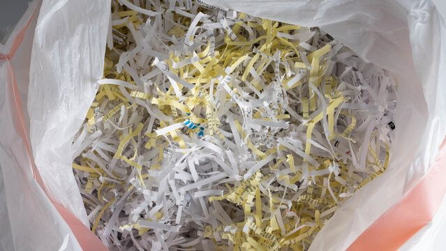 White plastic bag filled with shredded papers, documents, data security, recycling concepts. Close-up.