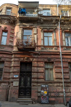Weathered facade of an old apartment building with carved door and iron balcony, Tbilisi, Georgia