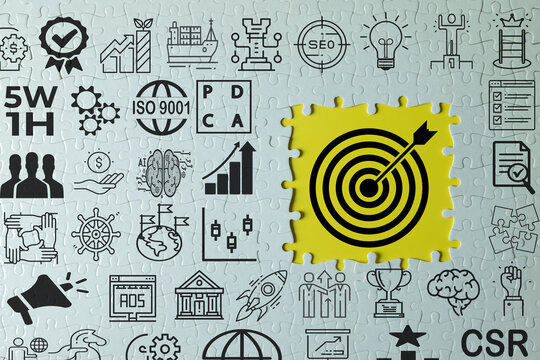 White jigsaw puzzle with business management icons and a missing section revealing a yellow target with an arrow. Concept of achieving business goals, corporate strategy, and finding solutions.