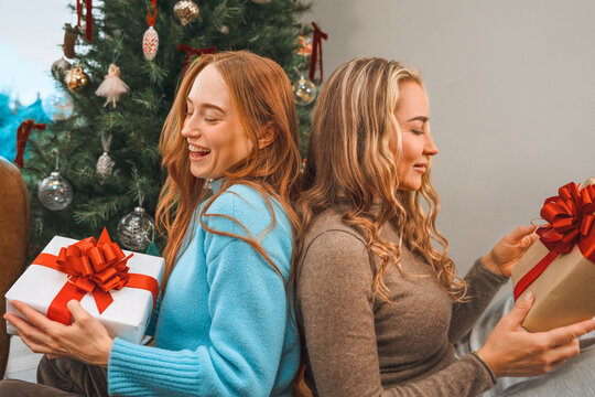 Women exchange wrapped gifts beside a decorated Christmas tree