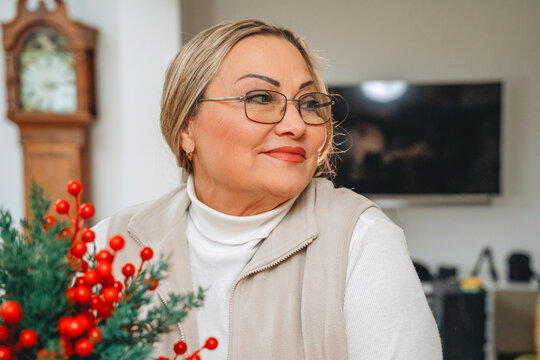 Woman sitting beside winter greenery in a living room