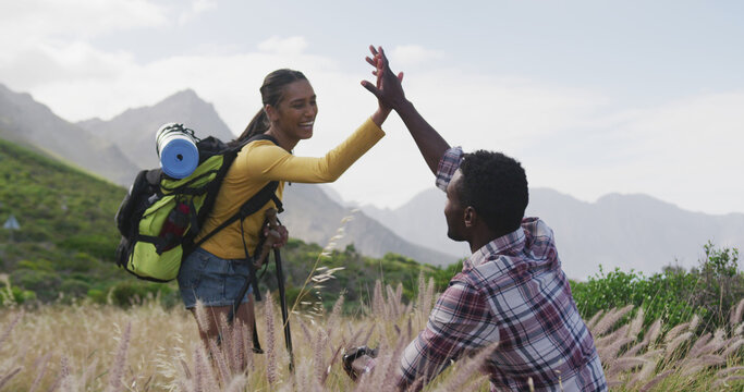 African american couple high fiving each other while trekking in the mountains