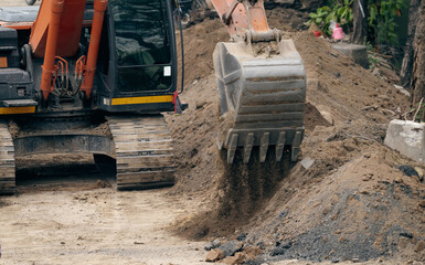 Backhoe working by digging soil at construction site. Bucket teeth of backhoe digging sand. Crawler excavator digging on soil. Excavating machine. Earthmoving machine. Excavation vehicle. Road repair. © Fahroni