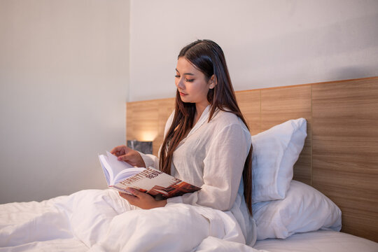 Young woman relaxing on bed while using reading enjoying learning and entertain story.	