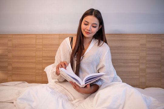 Young woman relaxing on bed while using reading enjoying learning and entertain story.	