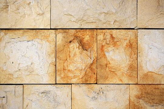 Natural limestone wall textures with rough rectangular blocks, weathered beige and rusty stains, architecture background for construction, interior design, building materials and masonry patterns