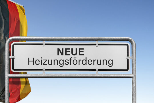 Symbolbild zur neuen Heizungsf&ouml;rderung in Deutschland mit Hinweisschild vor deutscher Flagge und blauem Himmel