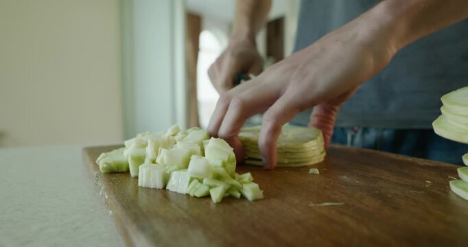 Close-up male hands cut zucchini with knife on wooden cutting board. 4K 10-bit