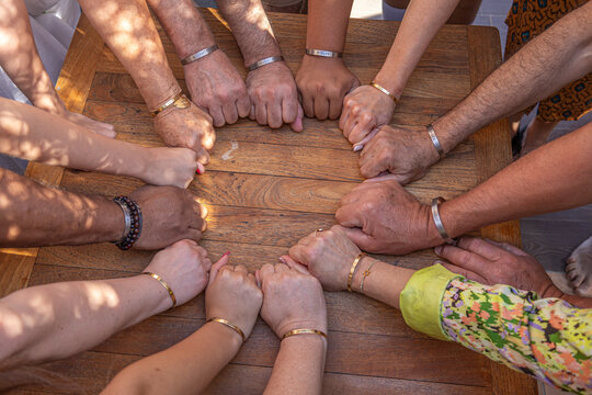 Hands Gathered Around a Wooden Table in a Circle