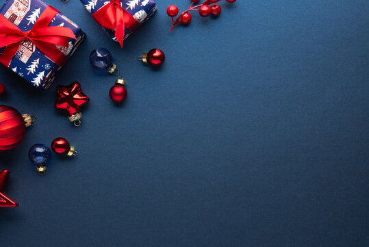 Merry Christmas and Happy Holidays greeting card, frame, banner. New Year. Red Christmas ornaments and gifts, presents on blue background top view. Xmas holiday festive theme. Christmas decoration.