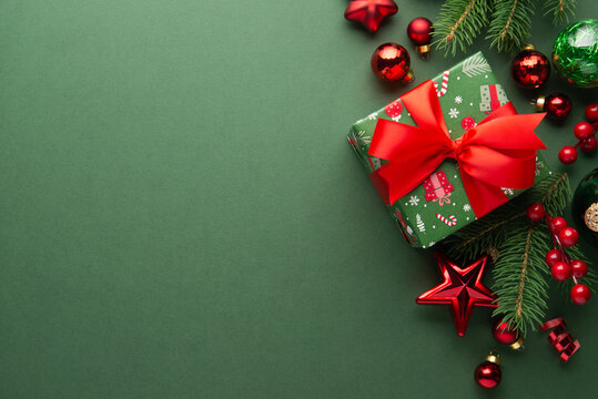 Green Christmas and Happy New Year holiday background with gift boxes, red ribbon bows and festive red ornaments, flat lay with copy space. Greeting card.