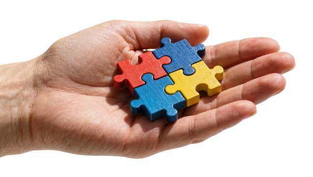 Human hand holding four colorful interlocking wooden jigsaw puzzle pieces