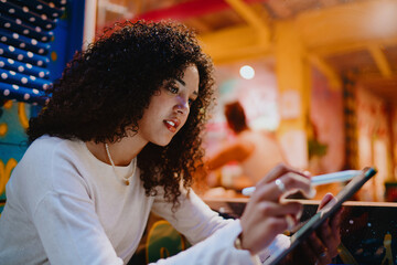 Focused young Hispanic woman using digital pad and stylus pencil in creative studio, concentrated girl reading online or working on project, remote freelance lifestyle concept © BullRun