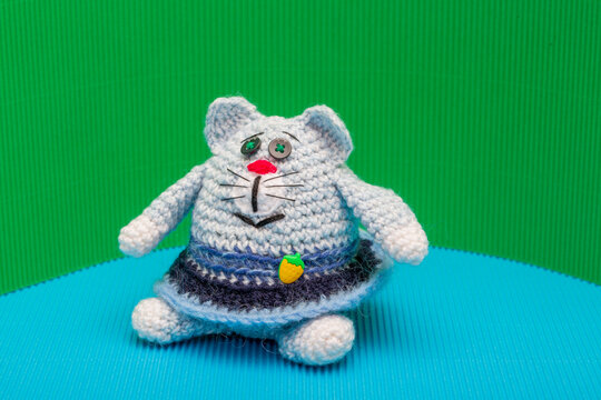 Cat crocheted from yarn against a colorful background