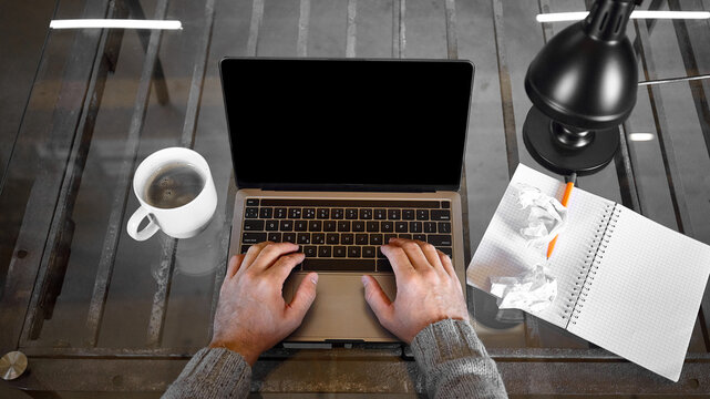 Writer typing on laptop beside notebook and crumpled paper on glass desk, overhead view. Copywriting services, creative blocks and digital publishing concept.