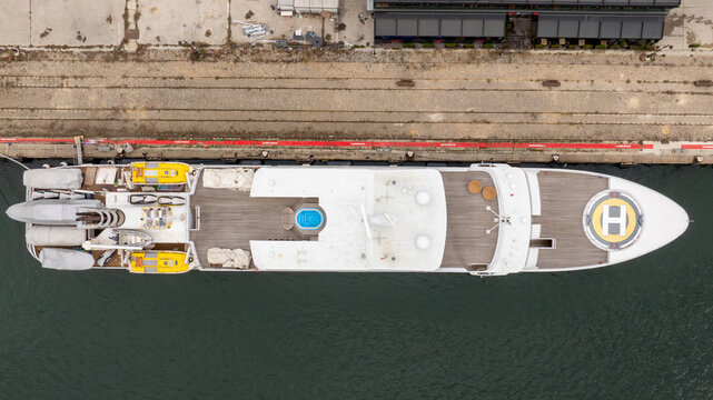 Aerial Top-Down View of Luxury Superyacht Docked in Marina with Helipad, Pool, and Tender Boats, Drone Shot of Private Yacht Deck