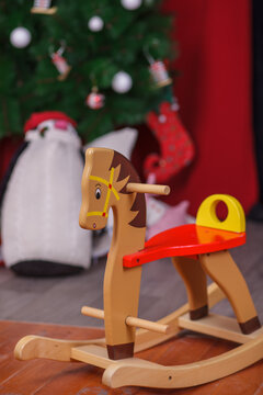 Classic Wooden Rocking Horse Toy on Floor with Christmas Decorations and Wrapped Gifts in Festive Holiday Room