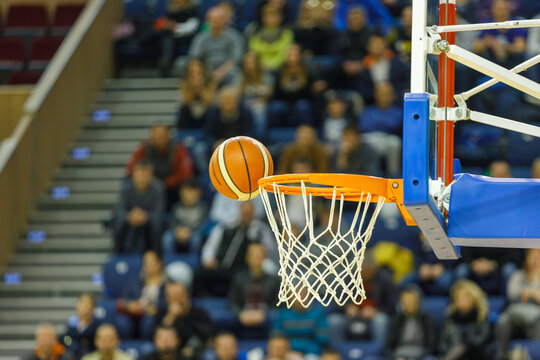 Basketball Bouncing on Rim of Hoop with Net in Sports Arena, Exciting Game Moment. Indoor Sports Arena with Spectators, Competitive Sports and Scoring Moment