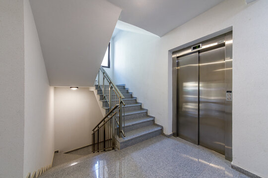 Modern Interior Hallway in Residential Building with Granite Staircase, Elevator and Railing