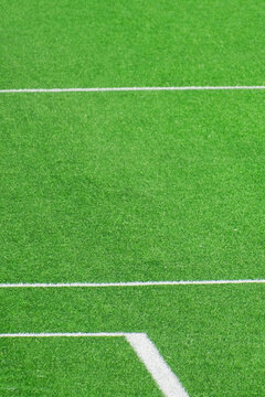 Green artificial turf field with white and yellow lines in football soccer sport stadium outdoors. Vertical sports background with copy space