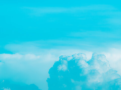 Saturated turquoise cyan sky with wispy cirrus streaks and a cumulus cloud rising from the bottom, vibrant surreal pastel sky background with copy space