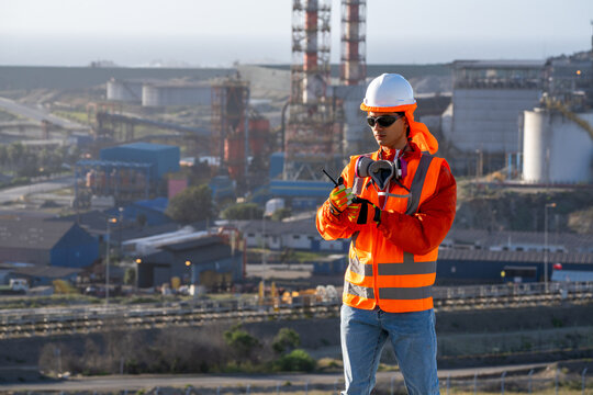 Industrial worker in high-visibility gear communicating by radio at a factory