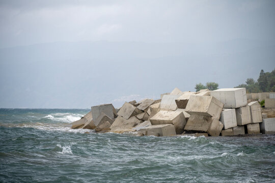 Heavy cubic concrete blocks lined up along a breakwater to dissipate wave energy and protect the coast