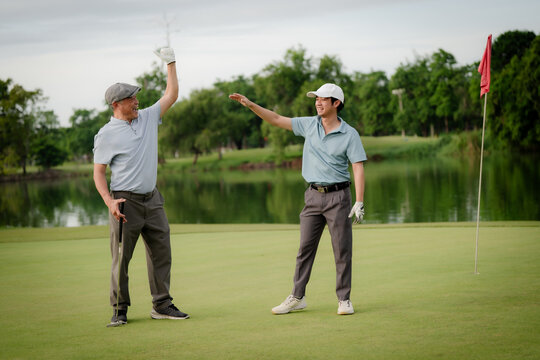 Active aging and golf friendship concept. Happy senior golfer shakes hands with a younger man on a green golf course, celebrating a friendly game. Golf, senior, handshake, friendship, sports.