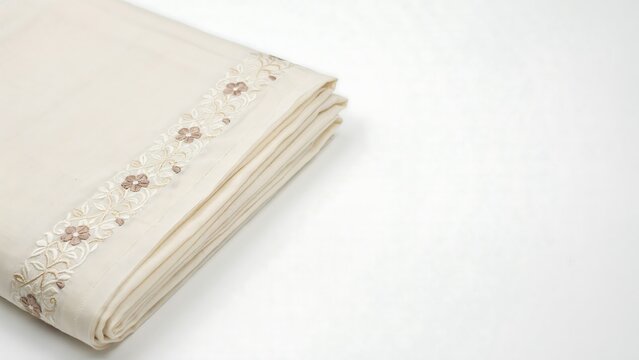 Folded cream fabric with delicate floral embroidery on white background