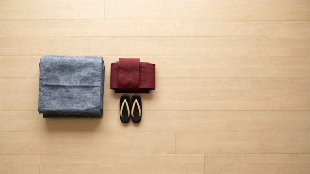 Traditional Japanese yukata kimono with red obi belt and wooden sandals on light wooden floor