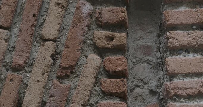 Ancient brick wall texture with geometric patterns, weathered red and orange clay bricks in vertical and diagonal herringbone rows, historic architecture detail