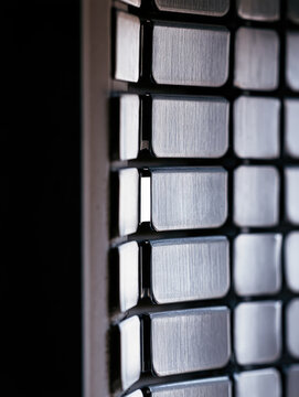 Closed steel ventilation damper with interlocking blades, brushed metallic texture, sharp edge highlight, functional industrial detail and dark negative space