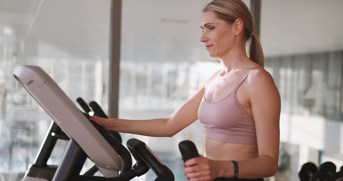 Woman training on elliptical cross trainer machine at gym