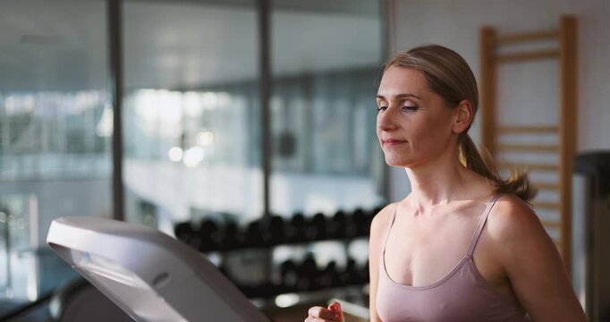 Determined woman running on a treadmill at the heath club gym