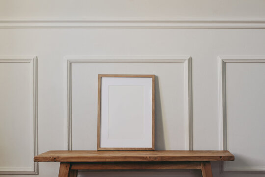 Blank Vertical Wooden Picture Frame Mockup on Rustic Oak Console Table Against Elegant White Wall with Decorative Molding. Minimalist Scandinavian Interior, Neutral Nordic Home Decor, Poster Template