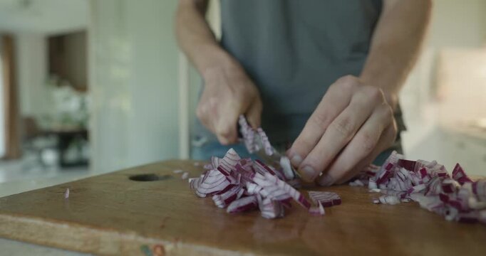 Close-up male hands cut onion with knife on wooden cutting board. 4K