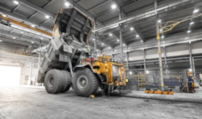 Large mining dump truck parked inside industrial workshop, blurred background © Parilov