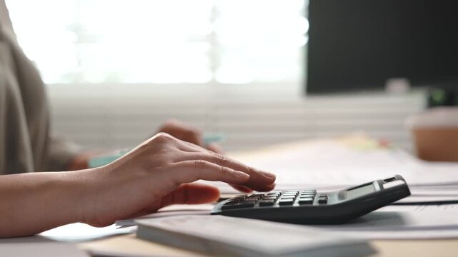 Accounting and finance, female accountant using calculator to check financial documents and expenses at office desk, tax calculation, budget analysis, balance sheet review and year end bookkeeping.