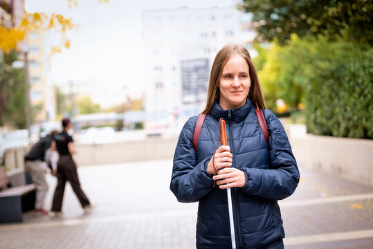 Visually impaired woman walking with a white cane in the city