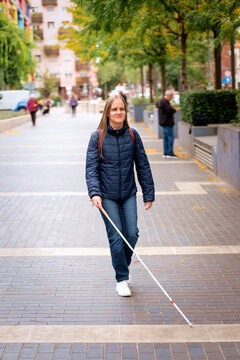 Visually impaired woman walking with a white cane in the city