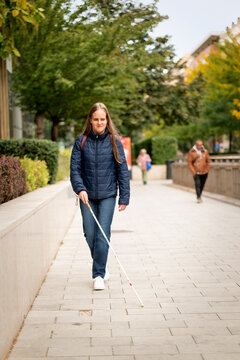 Visually impaired woman walking with a white cane in the city