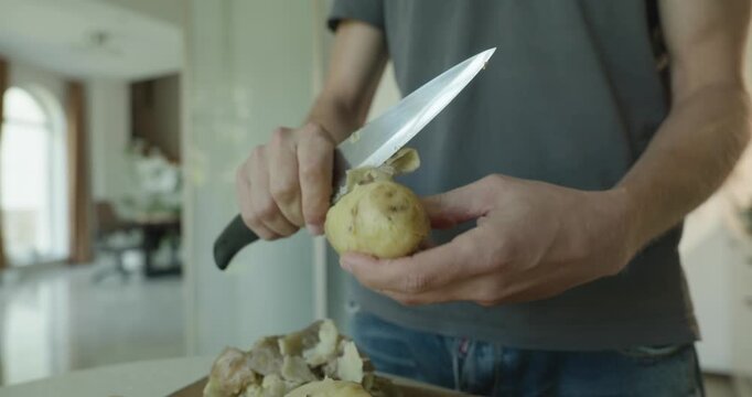 Close-up male hands peel boiled potato with knife. 4K 10-bit