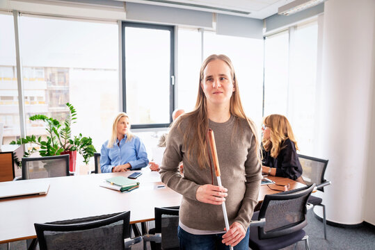 Portrait of a visually impaired businesswoman with white cane in an office