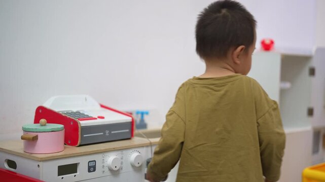 Young boy exploring a toy cash register in a play area
