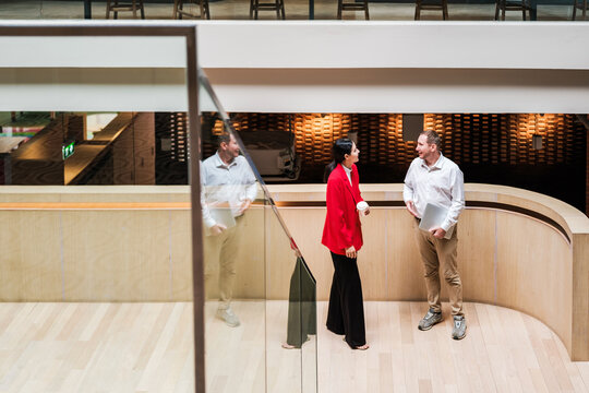 Colleagues talk beside a curved reception desk in a modern office