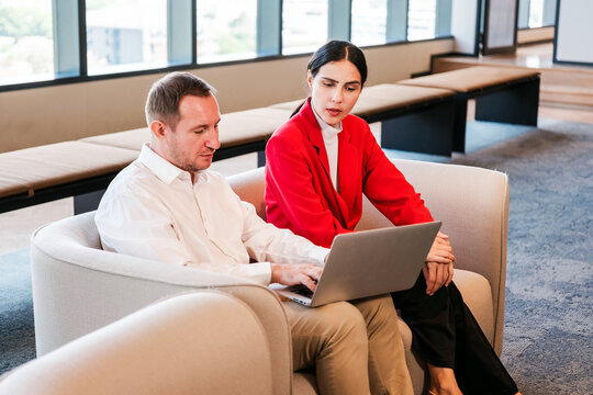 Coworkers review a laptop together in a modern office lounge